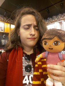 a girl looking at Dora the Explorer, wearing a Gryffindor scarf